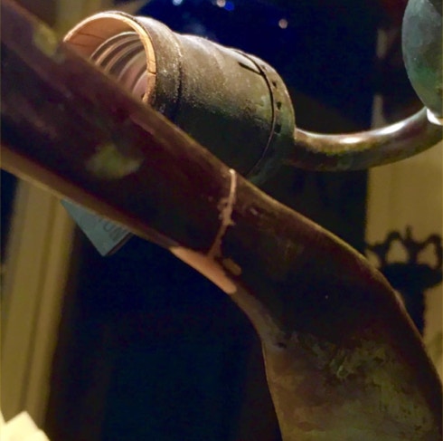 Close view of a repaired Tiffany-style lamp arm with the filled and blended joint nearly invisible
