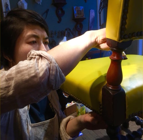 Koko working on the turned leg of a yellow upholstered antique chair