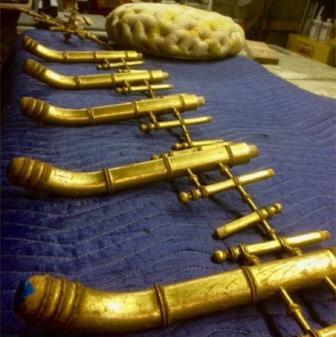 Gilded faux bamboo Victorian ottoman parts laid out on a blue moving blanket before reassembly