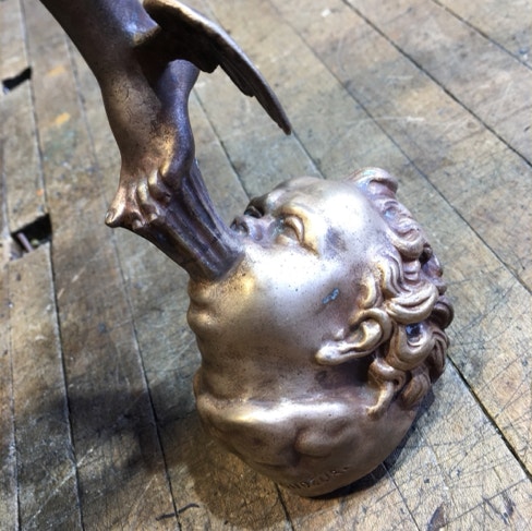 Underside of a bronze Mercury statue showing the head of Zephyrus separated from its stone plinth