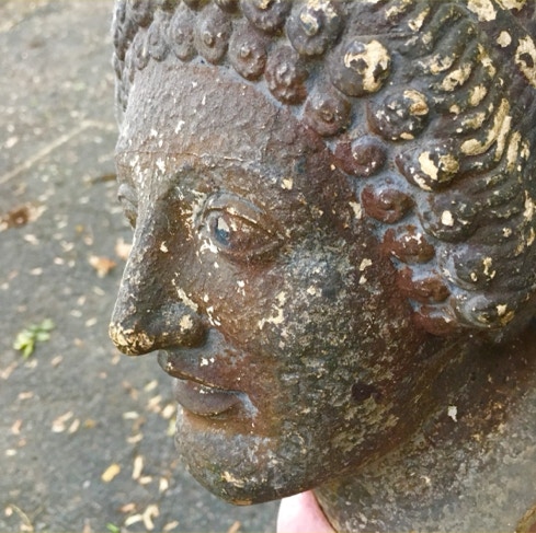 Weathered cast iron bust of a head with peeling paint and heavy surface corrosion