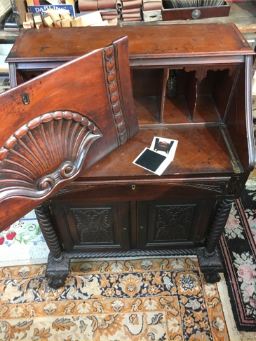 Antique mahogany secretary desk open on a shop floor with its broken original hinges removed