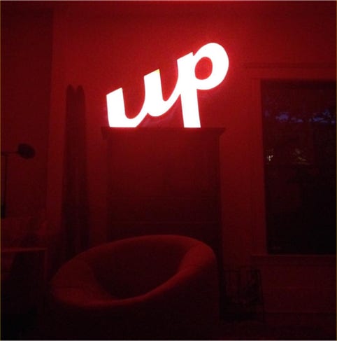 Illuminated up sign glowing red on a mantel in a darkened living room