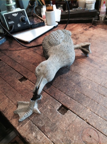 Ceramic garden duck figurine on a workbench with its beak being reattached