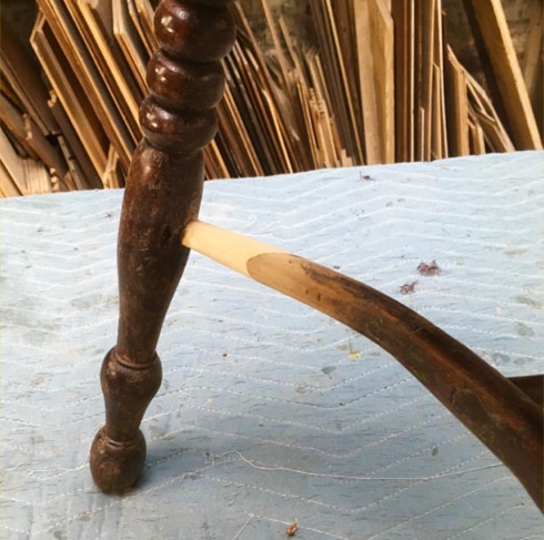 Pale newly shaped wooden stretcher fitted into the dark turned leg of an antique chair