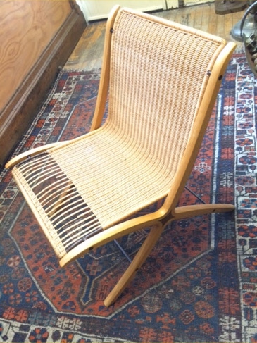 Mid-century Fritz Hansen Neilsen X folding chair with woven wicker seat and back on an oriental rug