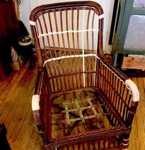 Antique wicker porch chair mid-repair with fresh wrapping at the arms and back