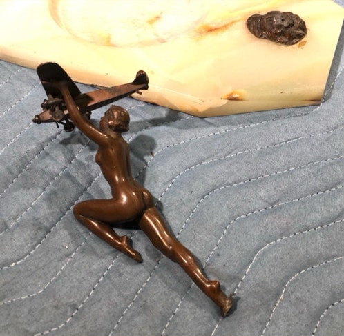 Bronze figure of a woman holding a biplane lying detached from its onyx base