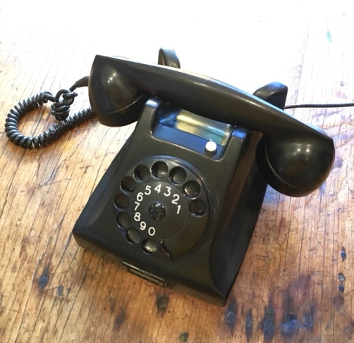 Black bakelite Dutch Ericsson rotary telephone assembled on a worn wooden workbench