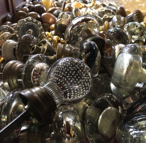 Dozens of antique glass and brass door knobs piled together, with a controlled bubble knob in front