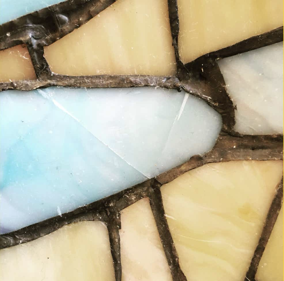 Macro view of a cracked pale blue glass panel in a leaded stained glass shade