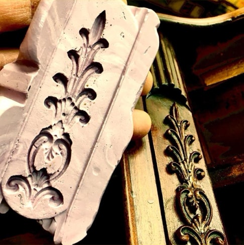 Silicone mold held beside the matching carved ornament on a gilded frame