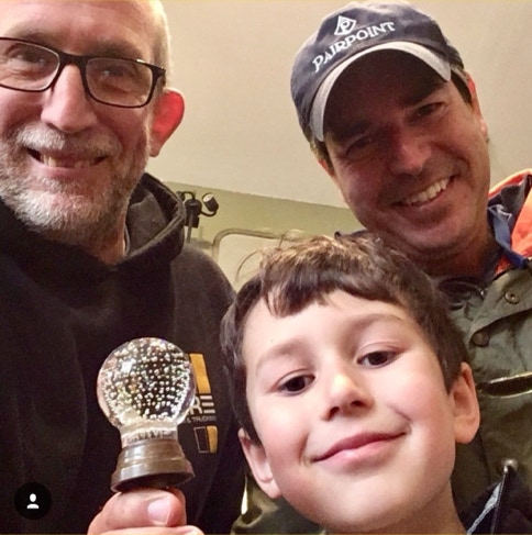 Two men and a boy smiling in the shop while holding an antique controlled bubble glass door knob