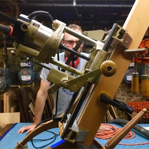 A craftsman using a lock mortiser jig on a wooden door
