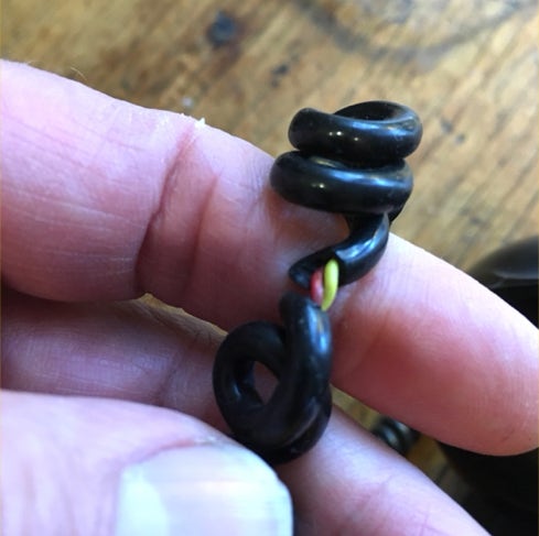 Fingers holding a coiled black telephone handset cord with the insulation broken through to bare wire