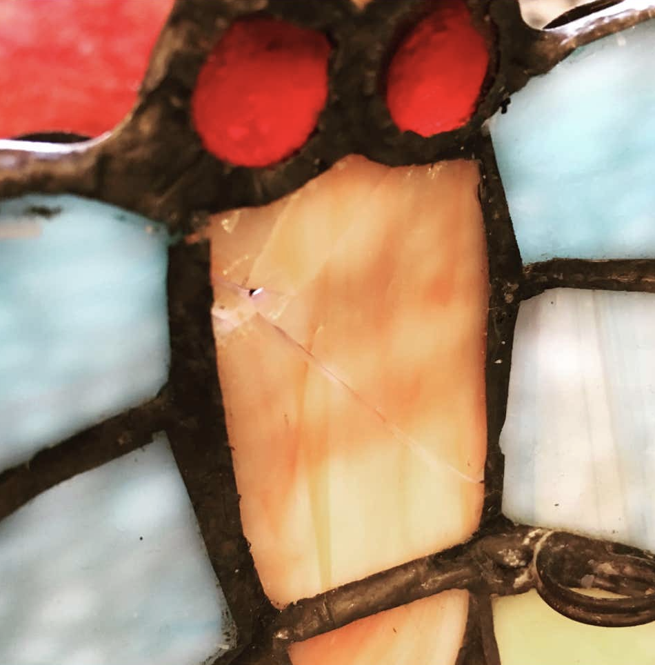 Macro view of a cracked amber glass panel beside red jewels in a leaded stained glass shade